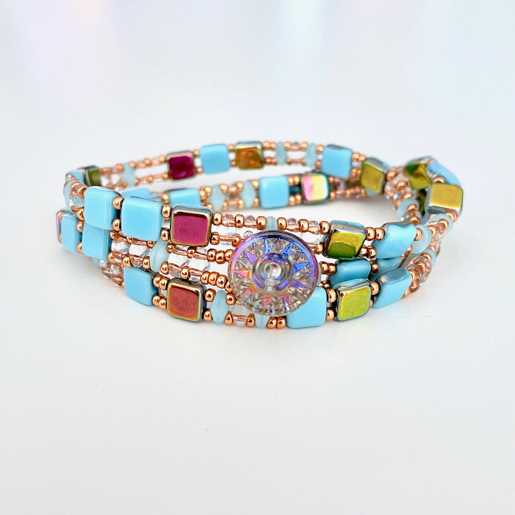 Czech tiles of light aqua blue and gold with light blue super duos and rose gold super duos make this 3 wrap bracelet.. Finished with a button