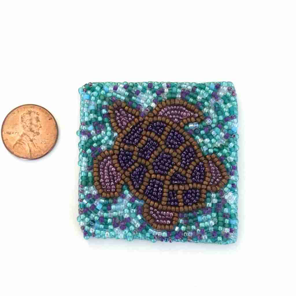 bead embroidered turtle panel shown with penny for size comparison