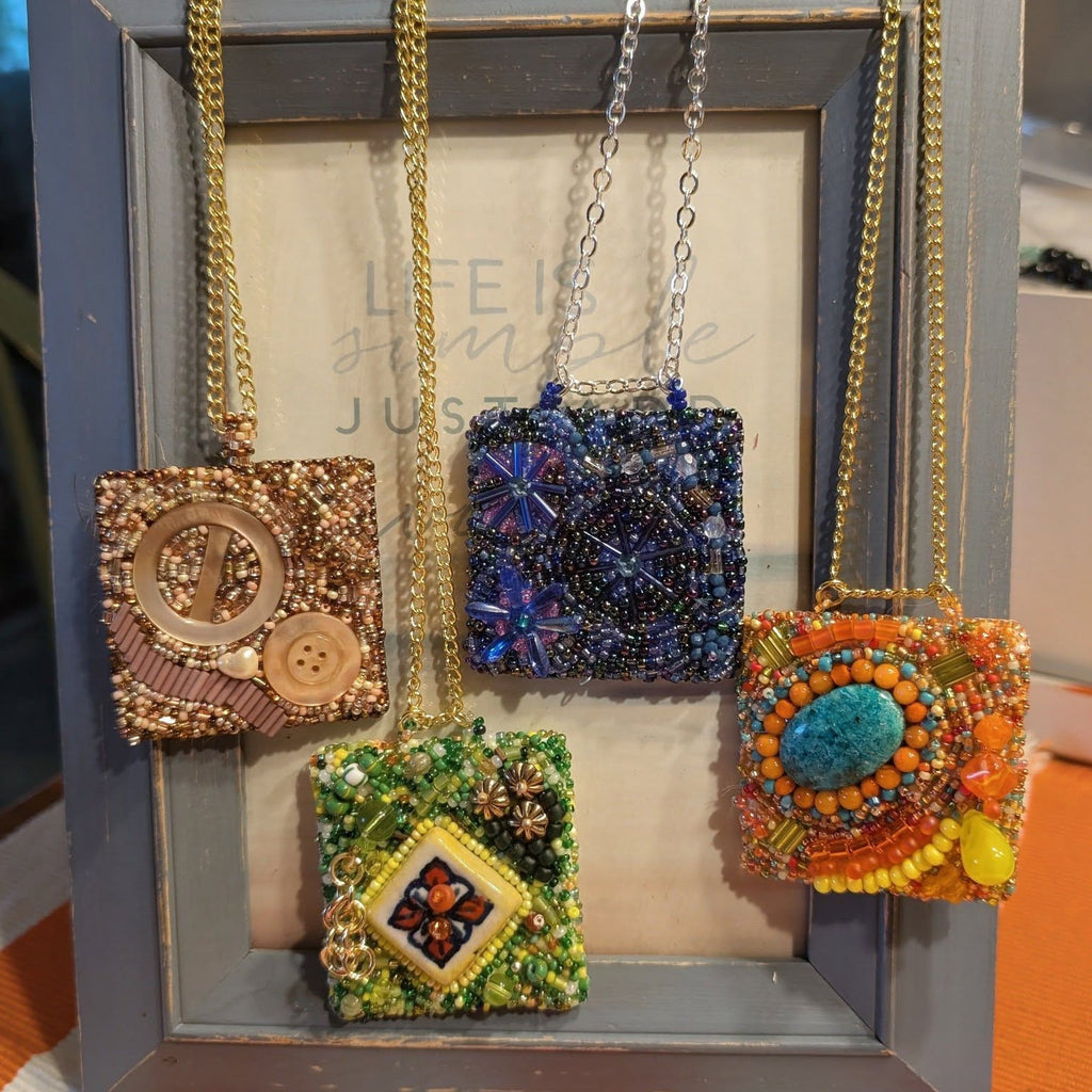 Colorful beaded pendants hanging from a frame on a striped fabric background