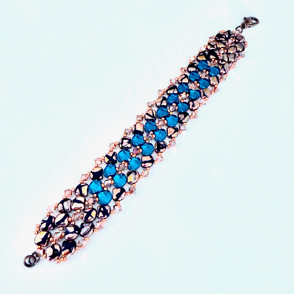 Beaded bracelet with blue and black ginko beads on a light blue background