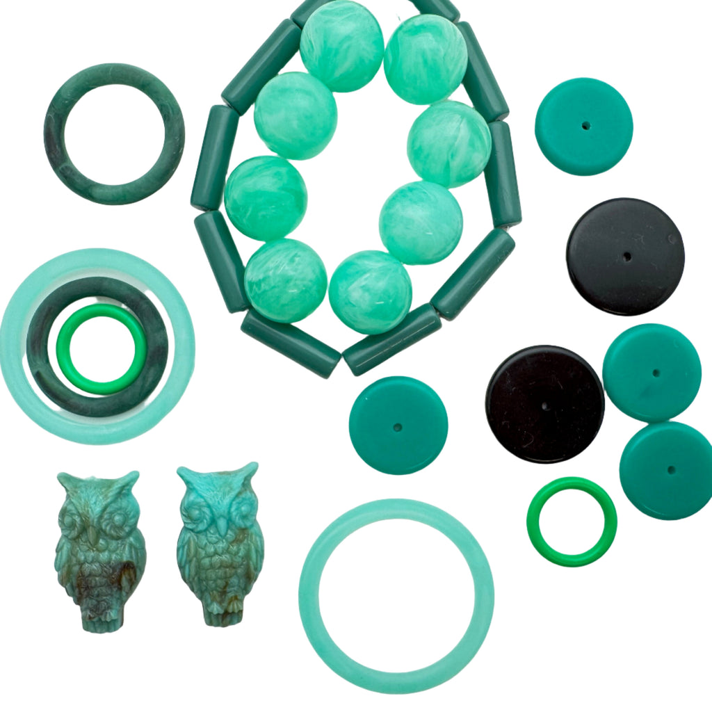 Collection of green and black beads and jewelry pieces on a white background