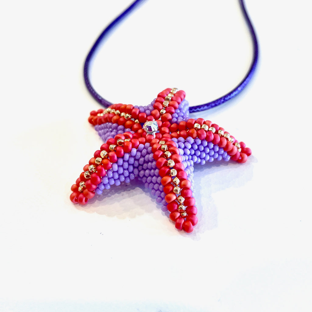 Starfish-shaped necklace with beaded design on a white background