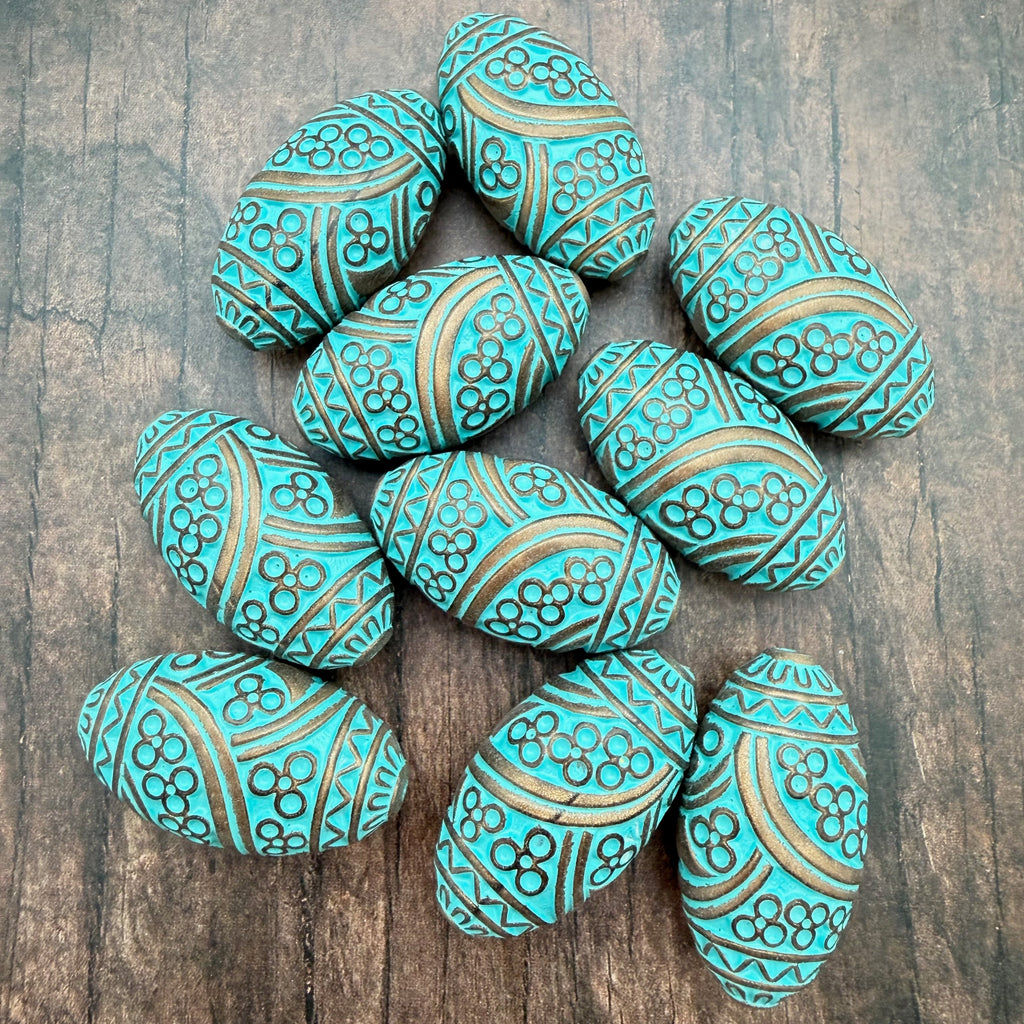 Decorative turquoise colored beads with gold patterns on a wooden surface