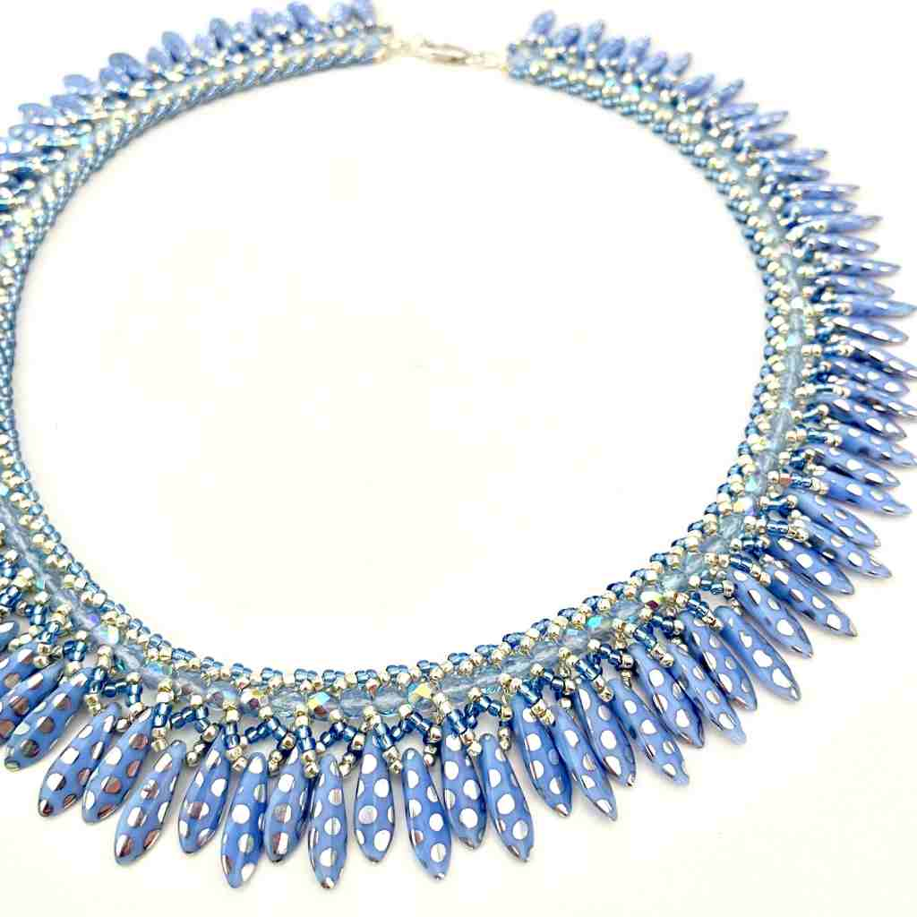 Blue beaded necklace with varying length daggers that go all the way around like a collar