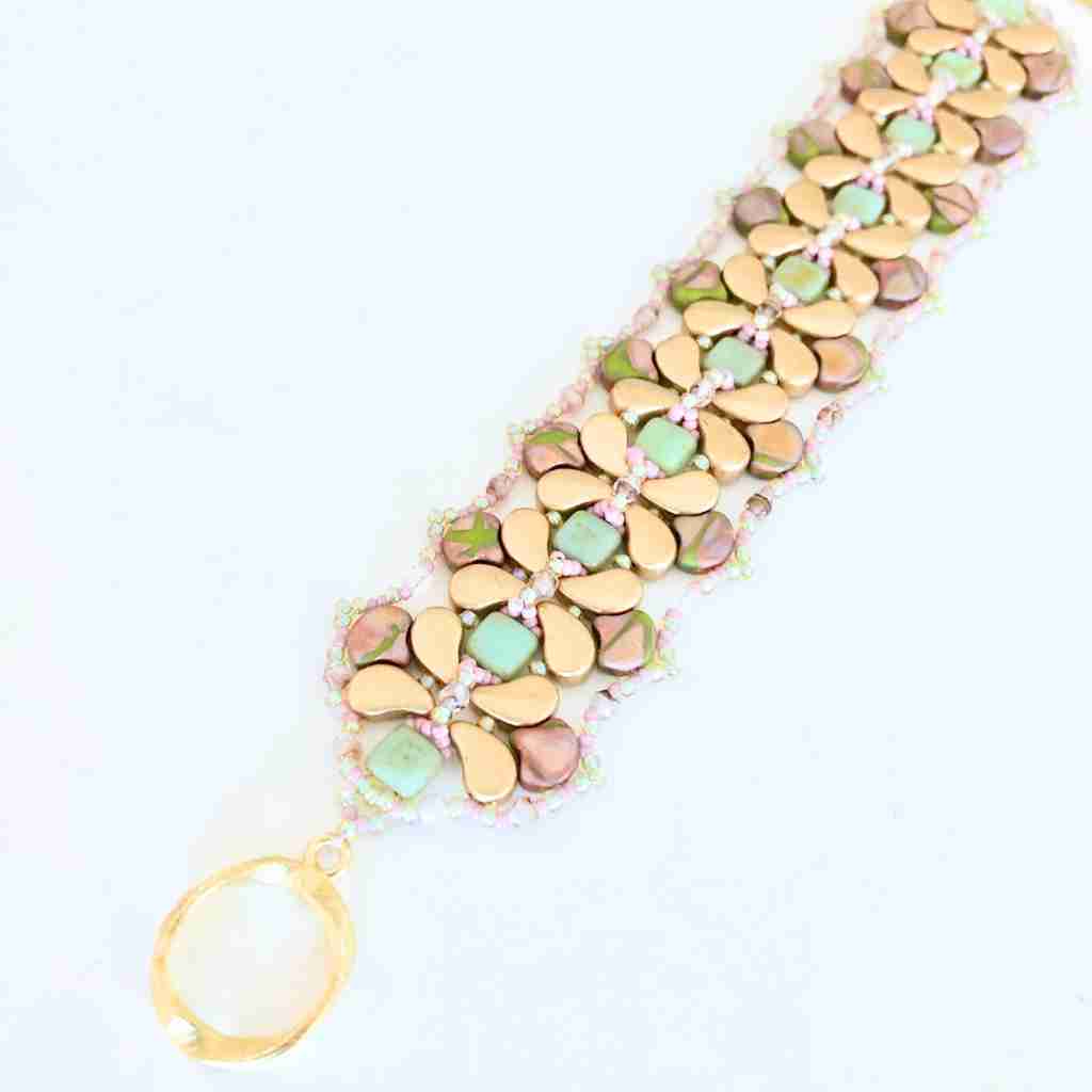 Beaded Bracelet with gold and green floral patterns on a white background