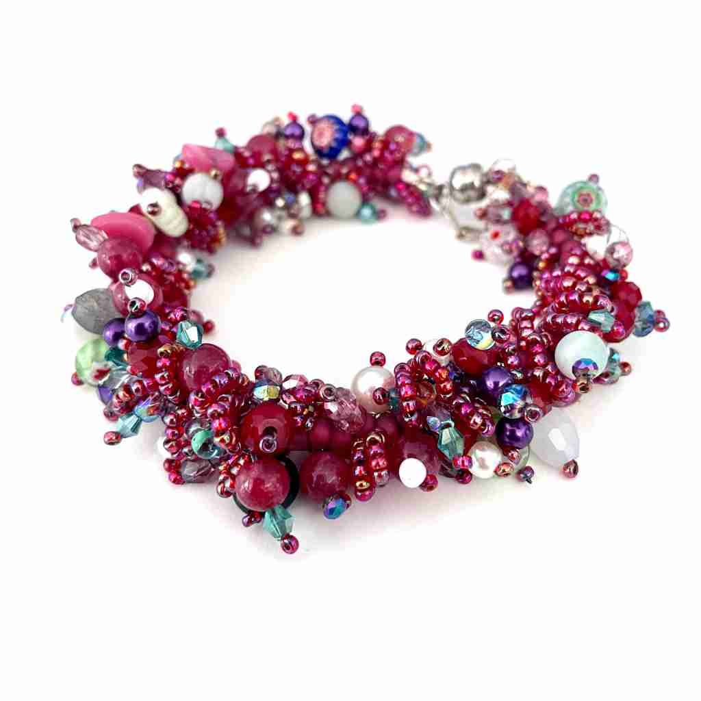 different shades of raspberry in a twisted bracelet  made with seed beads of different sizes, pearls and czech firepolish in shades of aqua. finished with a magnet clasp