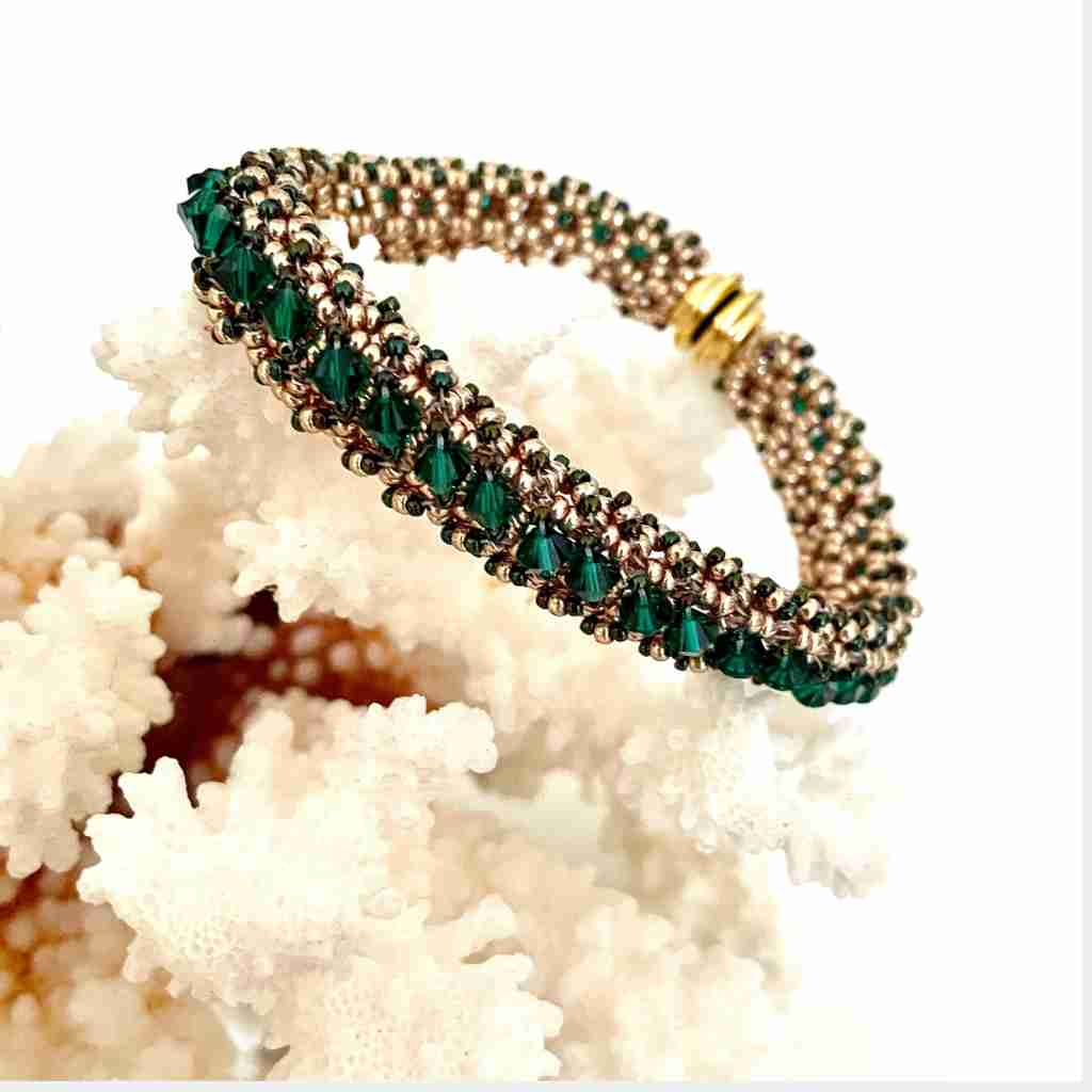 right angle weave bracelet with gold seed beads and emerald colored crystals