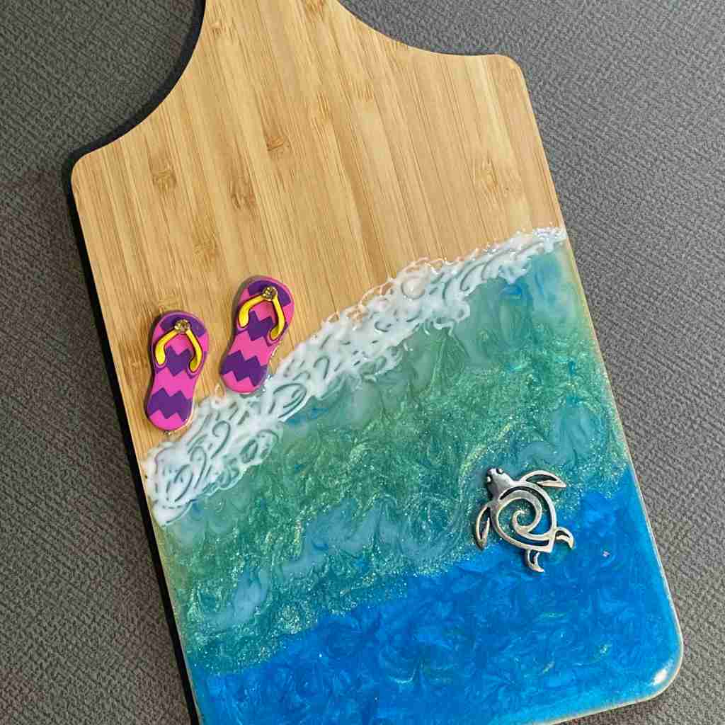 small decorative cutting board with ocean colored resin in wave pattern with turtle charm