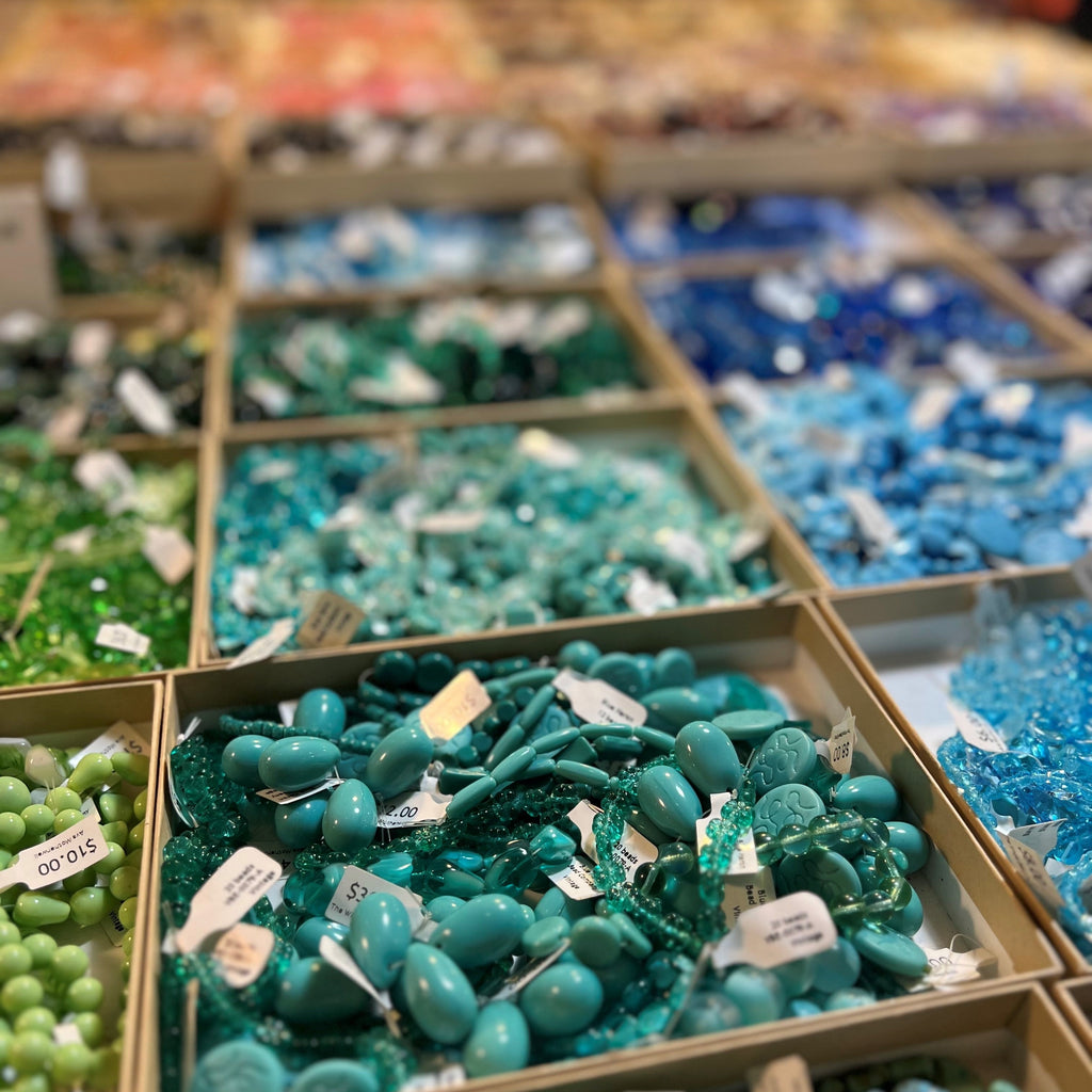 Display of colorful beads in boxes at a market or store.